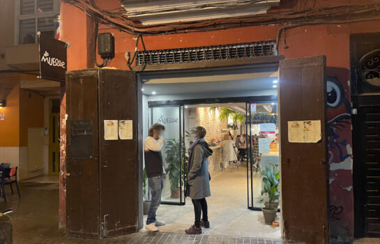 la puerta de entrada del restaurante el muelle con dos puertas de padera y dos personas hablando