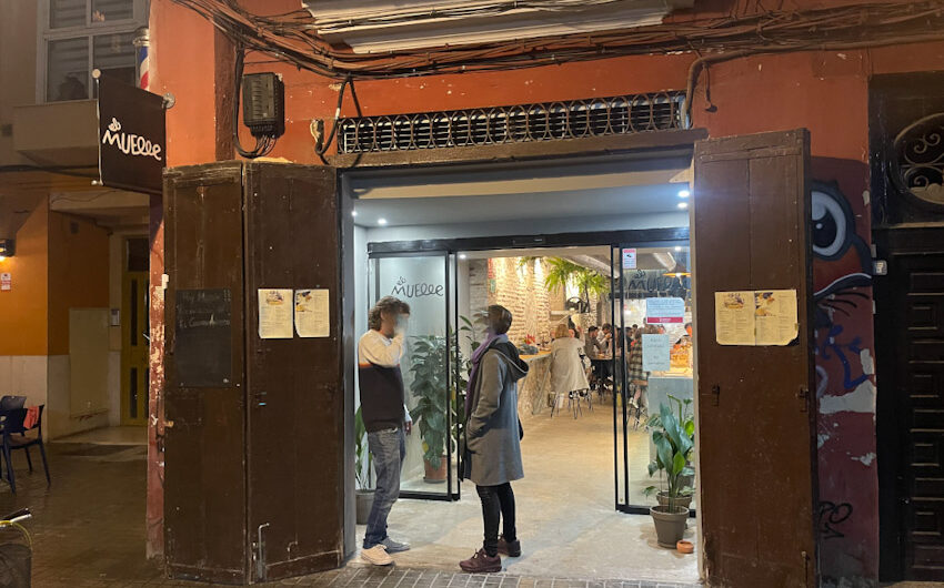 la puerta de entrada del restaurante el muelle con dos puertas de padera y dos personas hablando