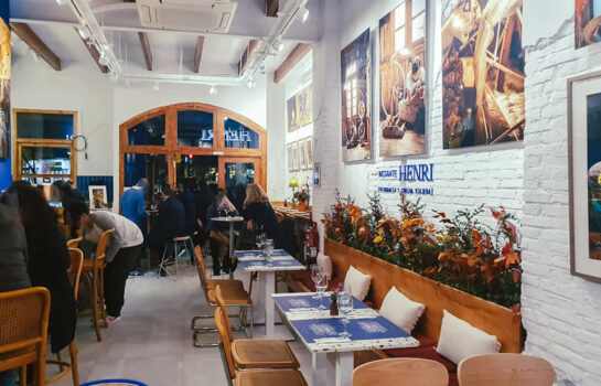 interior del restaurante Instante Henri con mesas y cuadros en las paredes